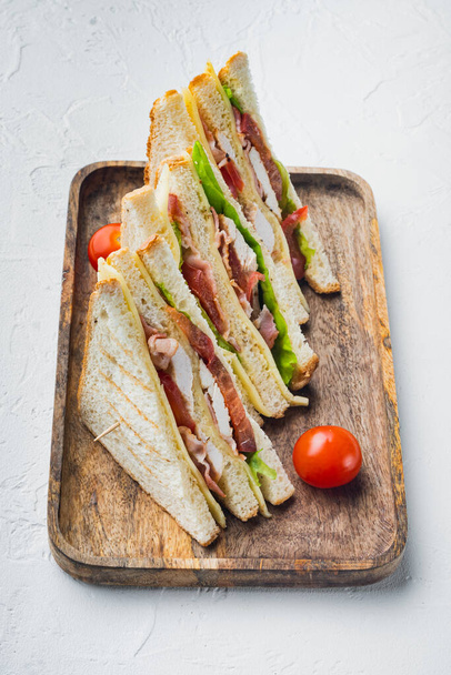 Homemade club sandwich made with turkey, bacon, ham, tomatoes, on white background - 写真・画像