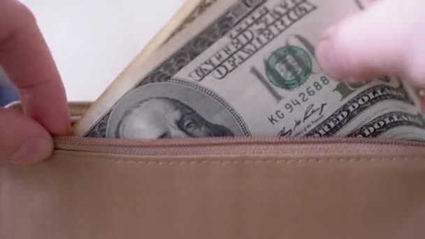 Les mains des hommes mettent de l'argent dans des centaines de billets de dollars en cuir marron portefeuille. Gros plan - Séquence, vidéo