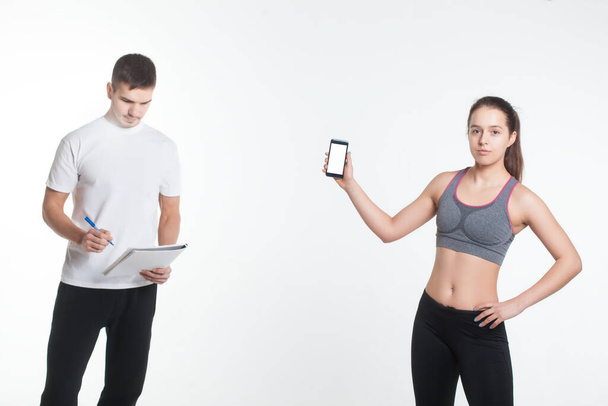 young female and male exercising with smartphone app online isolated - Foto, Imagen