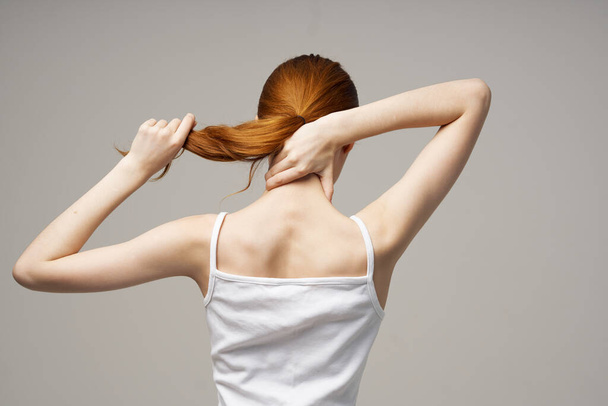 nainen t-paita koskettaa selkäänsä kädet takaisin näkymä - Valokuva, kuva