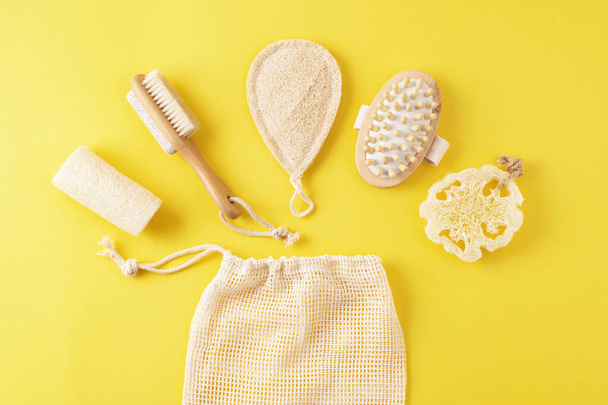 Natural hygiene skin care products set, wooden brush, massager. Sustainable lifestyle. Spa accessories on yellow surface. - 写真・画像