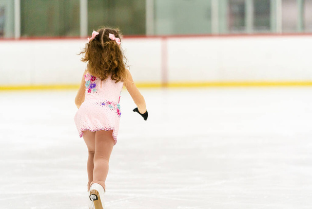 Petite fille pratiquant le patinage artistique sur une patinoire intérieure. - Photo, image