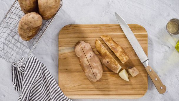 Flat lay. Step by step. Slicing russet potatoes in wedges with olive oil and spices to bake in the oven. - Foto, immagini