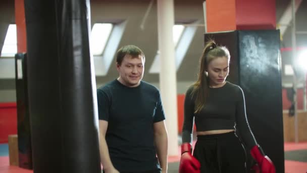 Entraînement à la boxe - une femme séduisante et son entraîneur de boxeur marche dans la salle de gym - regardant dans la caméra - Séquence, vidéo