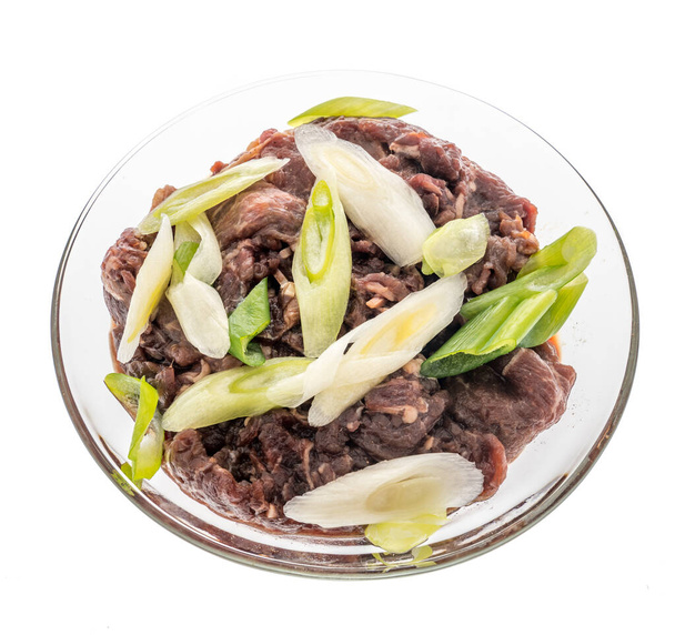 牛ブルゴギとネギをグラスボウルの中に入れ、韓国料理を孤立した背景で食べる - 写真・画像