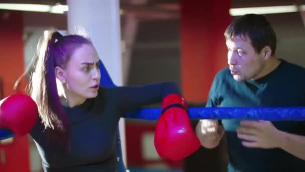 Een aantrekkelijke jonge vrouw rustend op de boksring en haar trainer praat met haar - Video
