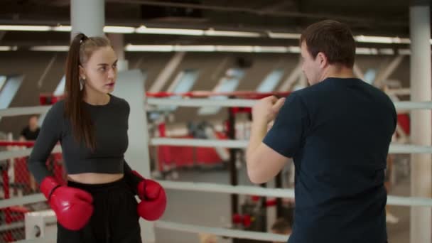 Entrenamiento de boxeo: una mujer atractiva que tiene un entrenamiento con un entrenador de boxeo - Imágenes, Vídeo