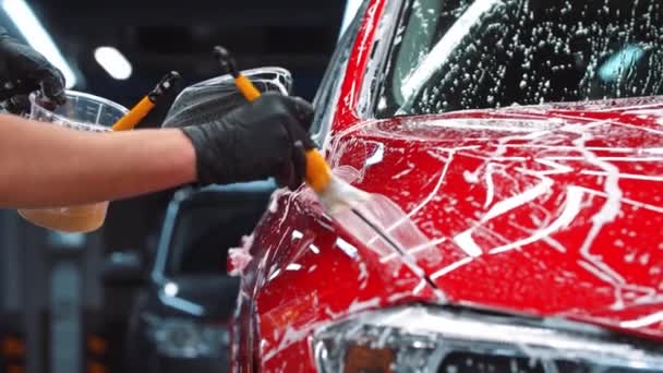 Servicio de limpieza automática - hombre aplicando una solución de limpieza en el coche rojo - Metraje, vídeo