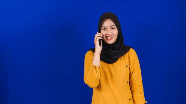 Asijské hidžáb žena nosí masku volání přítel izolované modré pozadí - Fotografie, Obrázek