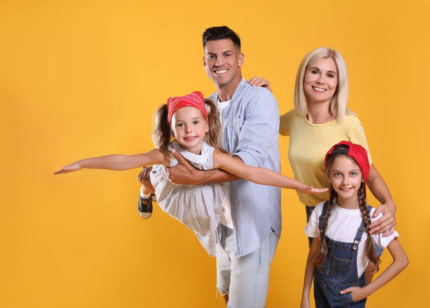 Portrait of happy family on yellow background - Φωτογραφία, εικόνα