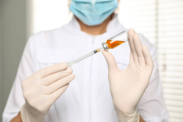 Doctor with vial and syringe in hospital, closeup. Vaccination day - 写真・画像