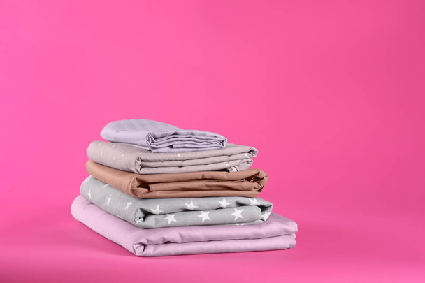 Stack of clean bed sheets on pink background - Foto, Imagem