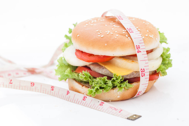 Cheeseburger avec ruban à mesurer sur fond blanc - Photo, image