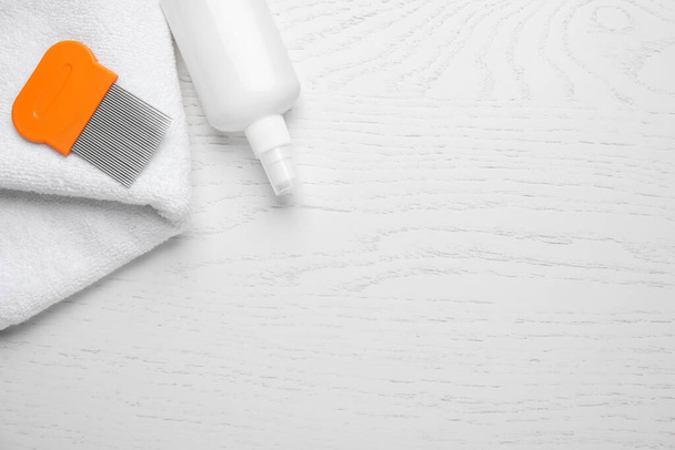 Spray, metal comb and towel for anti lice treatment on white wooden background, flat lay. Space for text - Valokuva, kuva