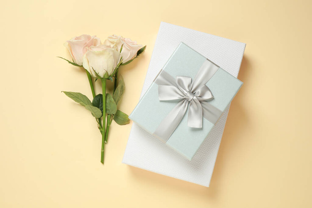 Elegant gift boxes and beautiful flowers on beige background, flat lay - Photo, Image