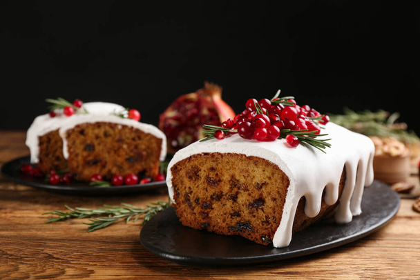 Traditional classic Christmas cake decorated with cranberries, pomegranate seeds and rosemary on wooden table - Photo, image