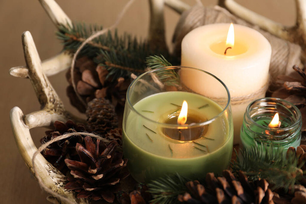 Burning scented conifer candles with Christmas decor on table, closeup - Fotoğraf, Görsel