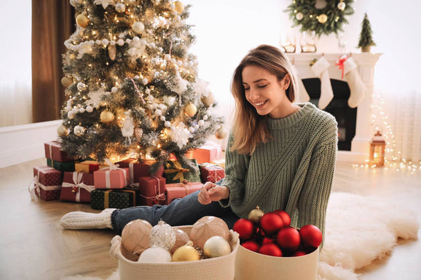 Beautiful woman decorating Christmas tree at home - Foto, afbeelding