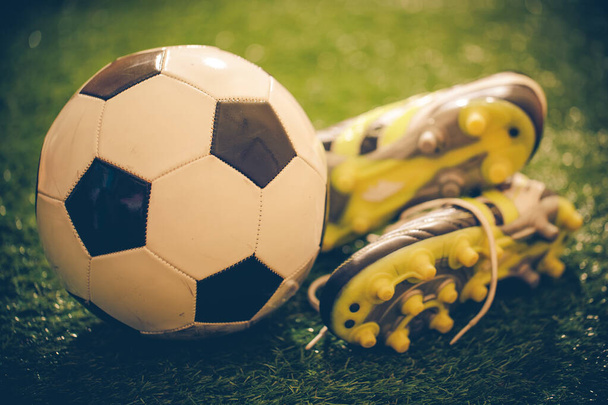 Fotbalové boty a fotbal na zelené trávou filtrované obrázek - Fotografie, Obrázek