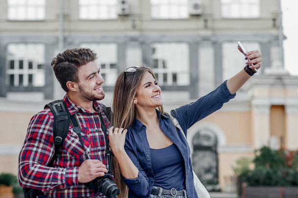 Happy couple of tourists taking selfie in showplace of city. - Foto, afbeelding