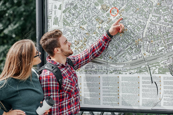 Young couple with a map in the city. Happy tourists sightseeing city with map. - Фото, изображение
