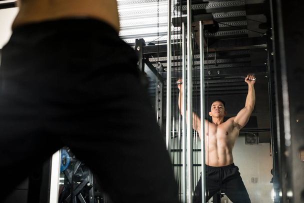 Formální a atletický čtyřicetiletý asijský samec se připravuje na pullupy. Cvičení a trénink scény v posilovně nebo fitness centru. - Fotografie, Obrázek