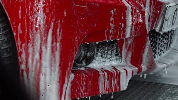 Autonpesupalvelu - punainen auto peitetty puhdistusvaahdolla - Materiaali, video