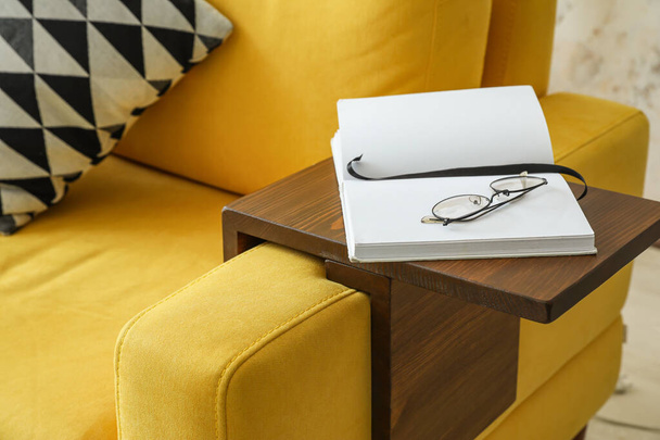 Óculos e livro sobre braço mesa no quarto - Foto, Imagem
