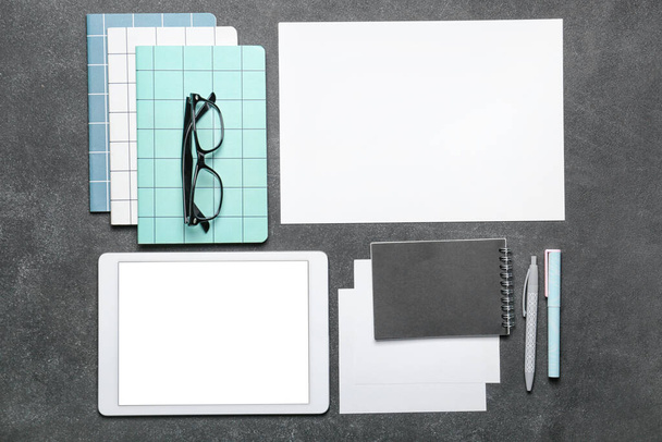 Samenstelling met blanco vel papier, tablet computer en stationair op donkere achtergrond - Foto, afbeelding