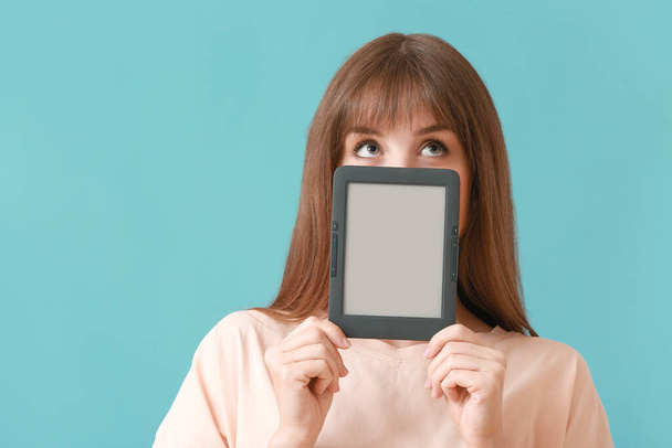 Young woman with e-reader on color background - Photo, image