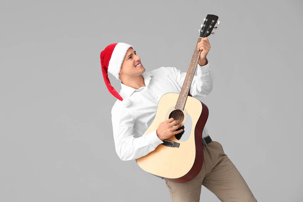Junger Mann spielt Gitarre auf grauem Hintergrund - Foto, Bild
