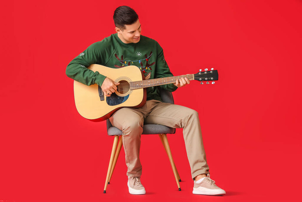 Young man playing guitar on color background - Fotó, kép