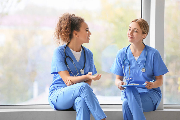 Ärztinnen sitzen auf Fensterbank in Klinik - Foto, Bild