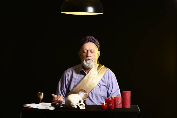 Чоловік за столом на темному фоні
 - Фото, зображення