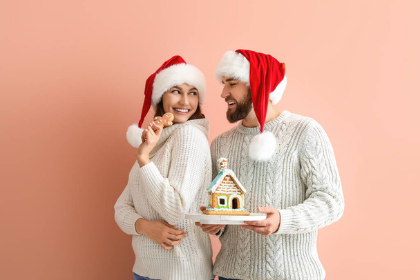 Onnellinen nuori pari piparkakut talon väri tausta. Joulujuhla - Valokuva, kuva