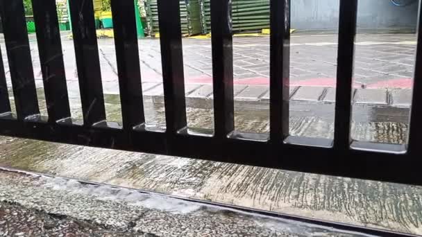 rain drops fall on concrete and black iron fence on the pedestrian street sidewalk in an urban area housing - Footage, Video