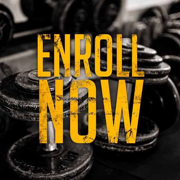 An enroll now announcement of a gym with yellow grungy font. Dumbbell rack as background. Possible Gym opening or any fitness related activity. - Photo, Image