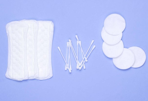 Hygiene products on blue pastel background. Cotton pads, women's pads, cotton ear sticks. Top view, flat la - Foto, immagini