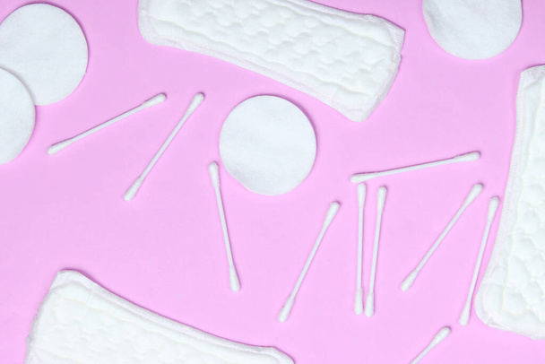 lat lay fondo con rama de algodón, almohadillas de algodón, orejeras, almohadillas femeninas sobre fondo pastel rosa - Foto, imagen