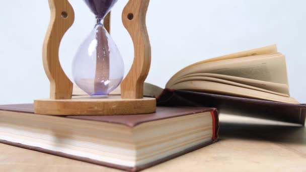 Pouring sand in an hourglass standing on an old books 4k - Footage, Video