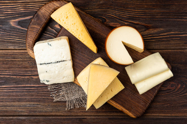 Cheese on dark wooden background. - Photo, image