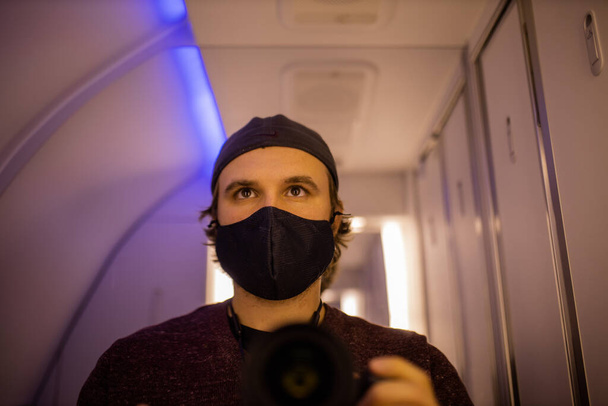 Αυτοπροσωπογραφία ενός άνδρα με μάσκα προσώπου στο μπάνιο του αεροπλάνου - Φωτογραφία, εικόνα