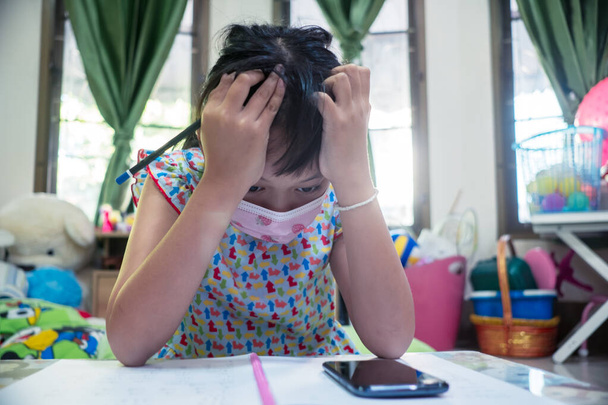 Σοβαρό κοριτσάκι μαθαίνοντας στο έξυπνο τηλέφωνο στο σπίτι με μάσκα προσώπου, Κοινωνική απόσταση κατά τη διάρκεια της καραντίνας, Online εκπαιδευτική έννοια - Φωτογραφία, εικόνα