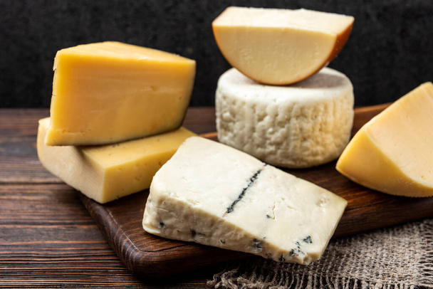 Cheese on dark wooden background. - Фото, зображення