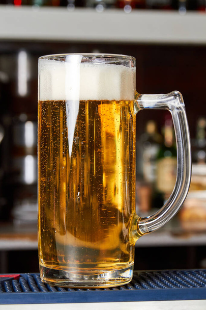 Стакан свежего пенного пива на барной стойке - Фото, изображение