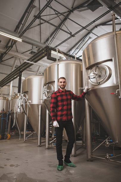 Low angle vertical shot of a professional brewer posing proudly at his brewery - Photo, Image