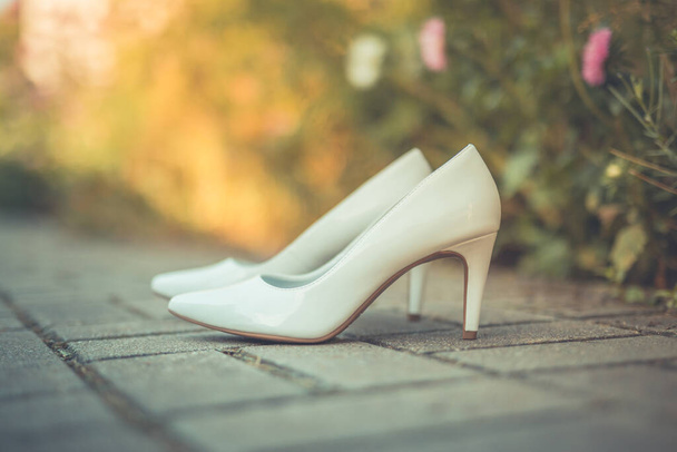 屋外の風景の中に花嫁の白い靴、ぼやけた自然な背景 - 写真・画像