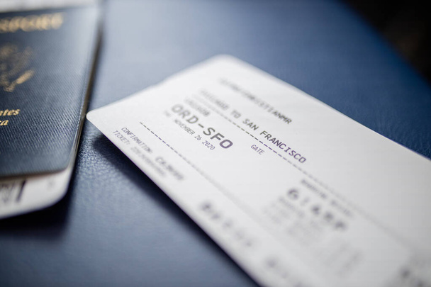 Vliegticket en Amerikaans paspoort boven een donkerblauwe stoel - Foto, afbeelding