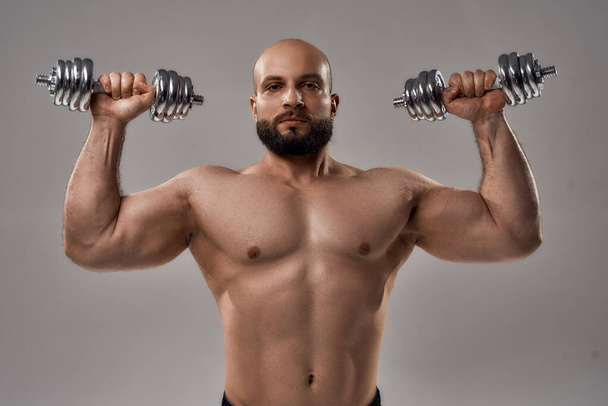 Young muscular caucasian athlete lifting dumbbells - Fotó, kép