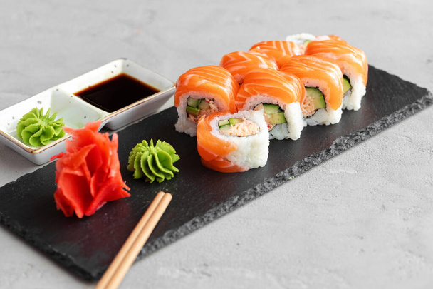 Sushi roll covered with fresh salmon served on plate - Fotoğraf, Görsel
